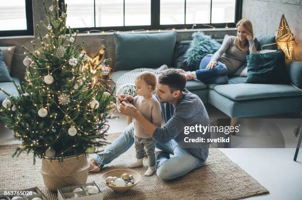 primera navidad en familia - decorar fotografías e imágenes de stock