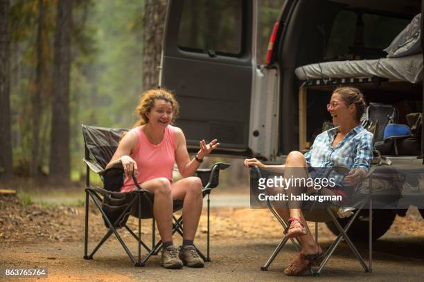zwei frauen in oregon wald camping - campingstuhl stock-fotos und bilder