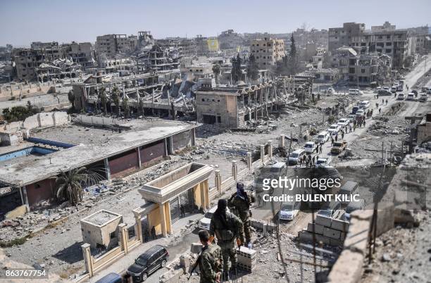 Fighters of the Syrian Democratic Forces stand guard on a rooftop in Raqa on October 20 after retaking the city from Islamic State group fighters....