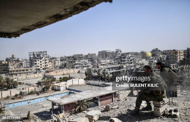 Fighters of the Syrian Democratic Forces stand guard on a rooftop in Raqa on October 20 after retaking the city from Islamic State group fighters....