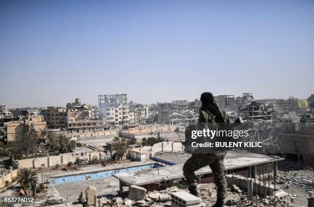 Fighter of the Syrian Democratic Forces stands guard on a rooftop in Raqa on October 20 after retaking the city from Islamic State group fighters....