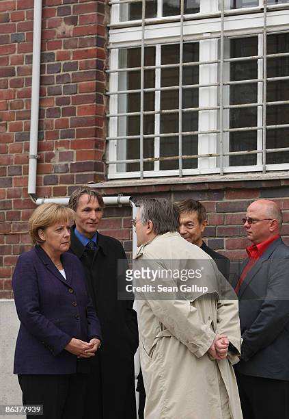 German Chancellor Angela Merkel speaks to former prison inmates Uwe Haedrich, Manfred Haferburg and Mirko Roewer while touring the former prison of...