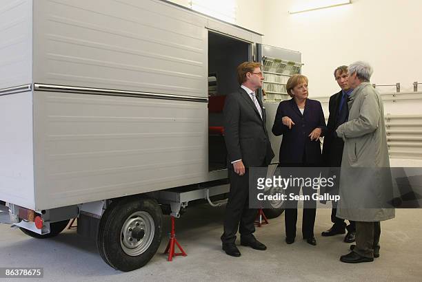 German Chancellor Angela Merkel stands next to a small truck once used for transporting prisoners while touring the former prison of the East German,...