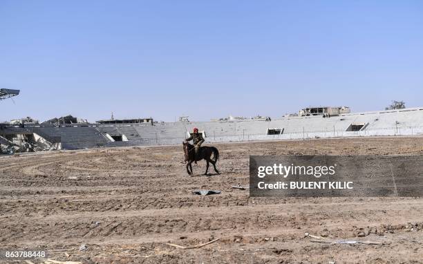 Fighter of the Syrian Democratic Forces rides a horse at the stadium in Raqa on October 20 as he celebrates with his comrades after they retook the...