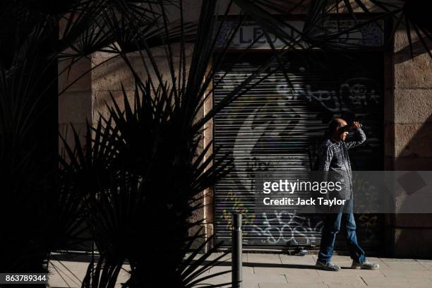 Man shields his eyes as he walks down the street in the afternoon sunshine on October 20, 2017 in Barcelona, Spain. The Spanish government is to take...