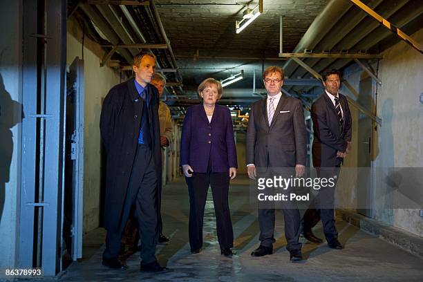 German Chancellor Angela Merkel speaks to current prison memorial director Hubertus Knabe and State Secretary Andre Schmitz while touring the former...