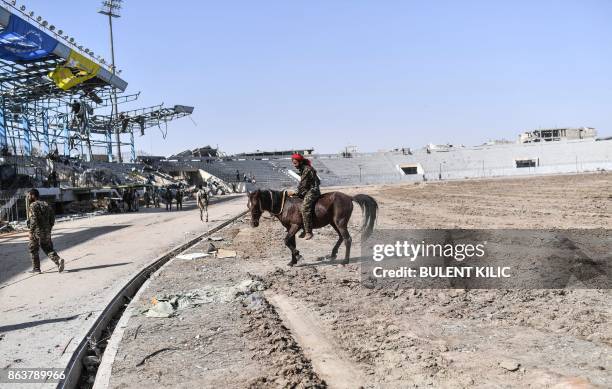 Fighter of the Syrian Democratic Forces rides a horse at the stadium in Raqa on October 20 as he celebrates with his comrades after they retook the...