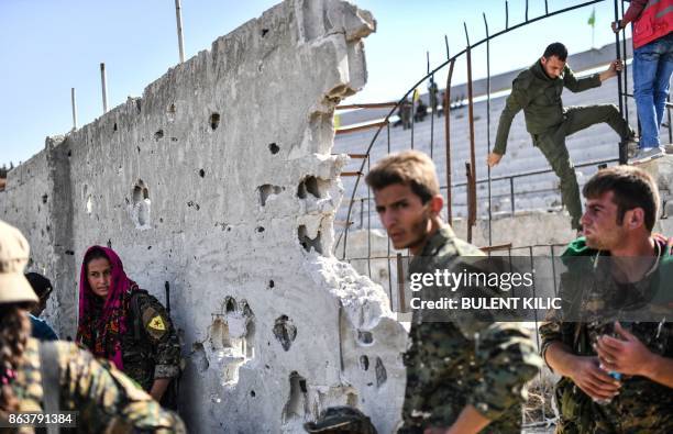 Fighters of the Syrian Democratic Forces gather at the stadium in Raqa to celebrate on October 20 after retaking the city from Islamic State group...