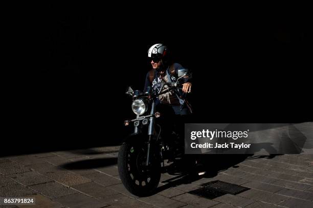 Man rides a motorbike in the afternoon sun down a narrow street on October 20, 2017 in Barcelona, Spain. The Spanish government is to take steps to...