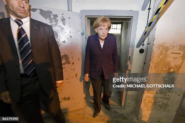 German Chancellor Angela Merkel looks at a prison cell as she visits the memorial site at the former Stasi, East German secret police at the eastern...