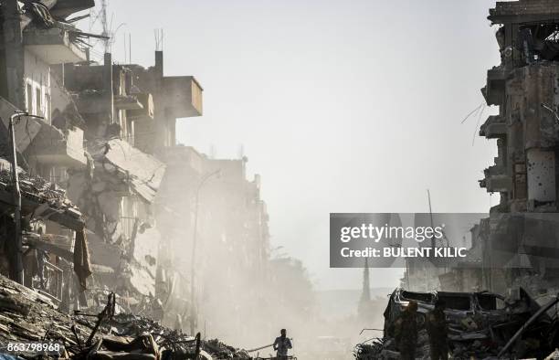 Syrian man runs down a street in Raqa past destroyed vehicles and heavily damaged buildings on October 20 after a Kurdish-led force expelled Islamic...