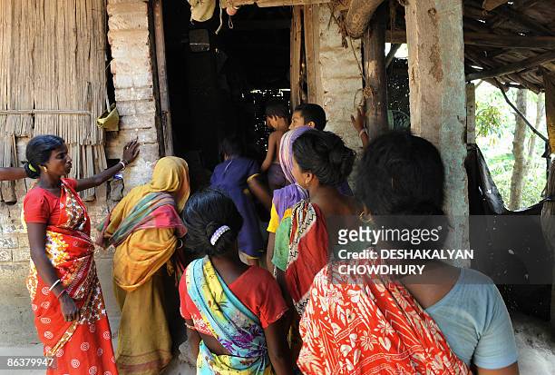 Indian villagers gather at the entrance to Madan Bera's hut to receive his body after he died drinking home brewed alcohol in Hogolberia village in...