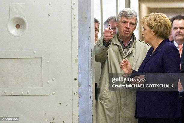 German Chancellor Angela Merkel inspects a prison cell with former prisoner Gilbert Furian as she visits the memorial site at the former Stasi, East...