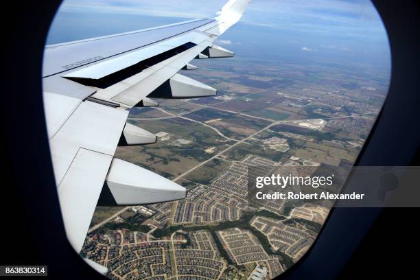 Housing developments fill the landscape below in a view from a passenger plane window as it flies east after departing Dallas/Fort Worth...