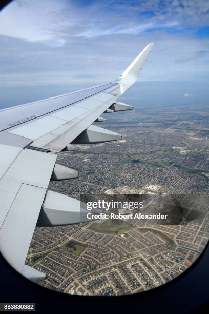 Housing developments fill the landscape below in a view from a passenger plane window as it flies east after departing Dallas/Fort Worth...