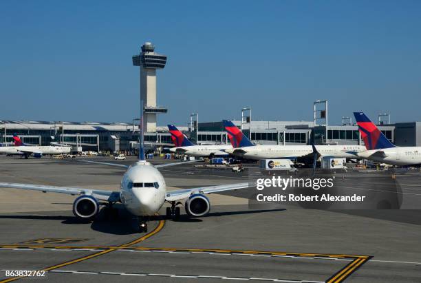 Delta Airlines passenger jet taxis at John F. Kennedy International Airport in New York, New York, with the airport's 32 story, 321-foot tall control...