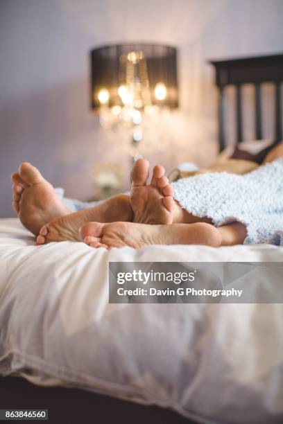 couple in bed - feet in bed stock pictures, royalty-free photos & images