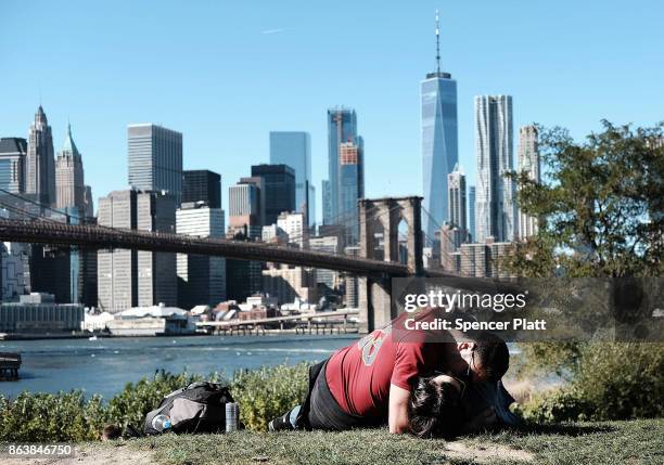 Couple embrace on the grass along a promenade in Brooklyn on an unseasonably warm day on October 20, 2017 in New York City. Temperatures across New...