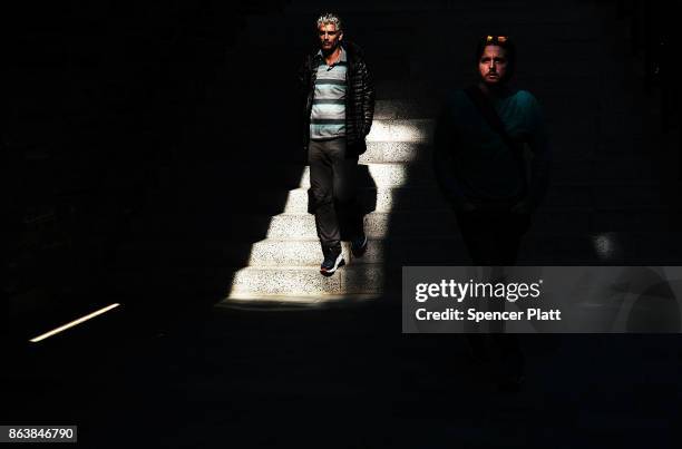 Men walk the the sunlight along a promenade in Brooklyn on an unseasonably warm day on October 20, 2017 in New York City. Temperatures across New...