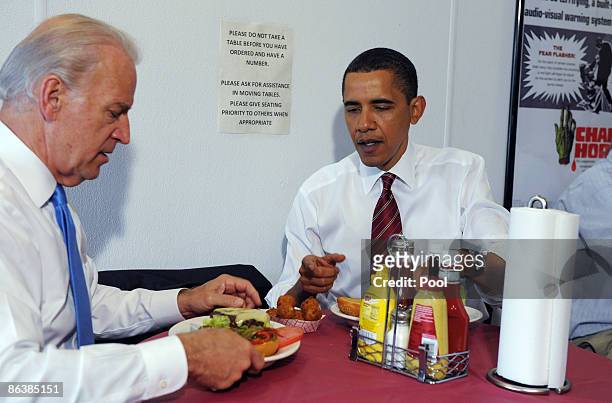 President Barack Obama and U.S. Vice President Joe Biden sit at a table with their cheeseburger lunch orders at Ray's Hell Burger May 5, 2009 in...