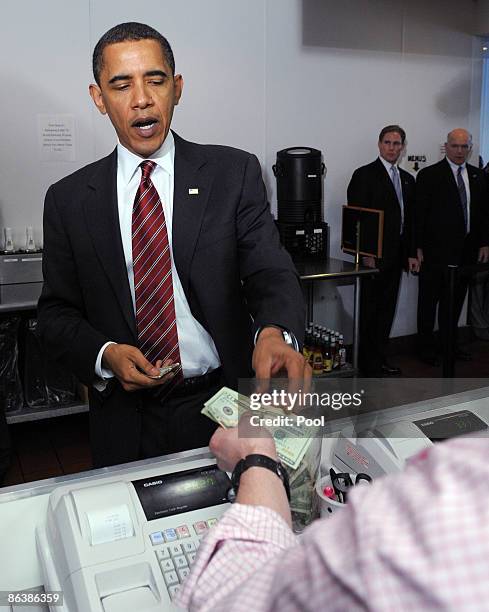 President Barack Obama pays after ordering lunch at Ray's Hell Burger May 5, 2009 in Arlington, Virginia. Obama and Biden made an unannouced vist to...