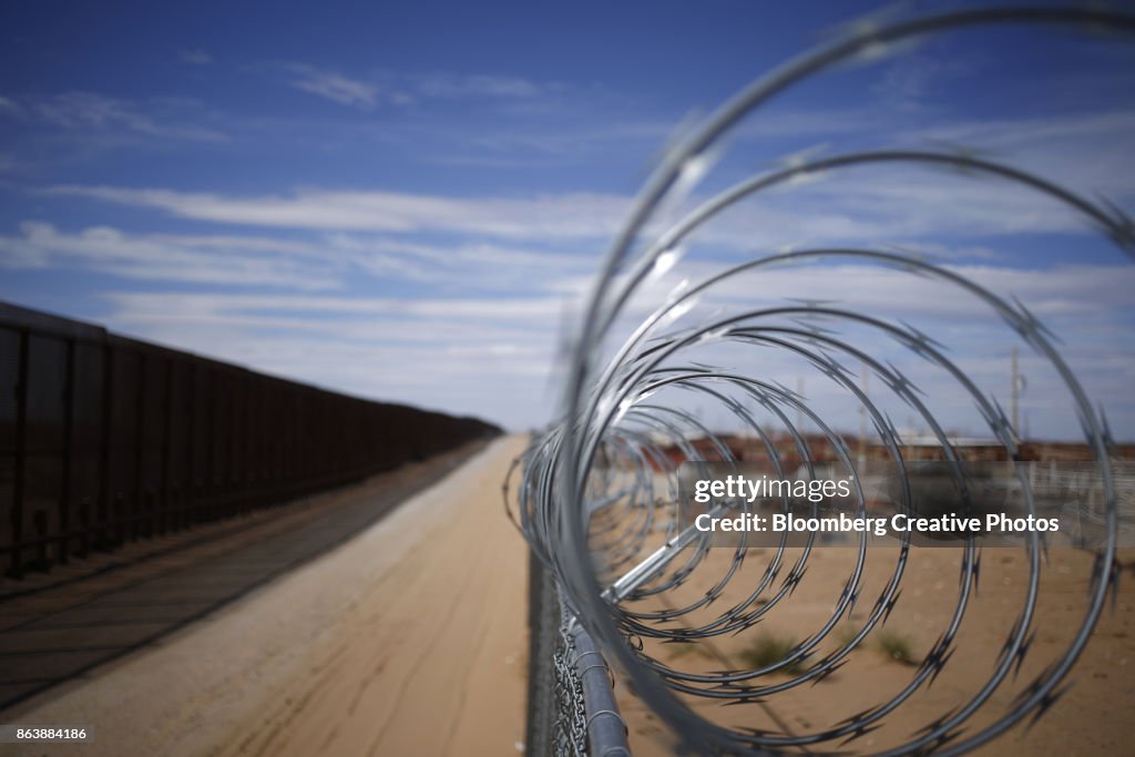 A concertina barbed wire fence stands next to a border fence that separates the U.S. and Mexico