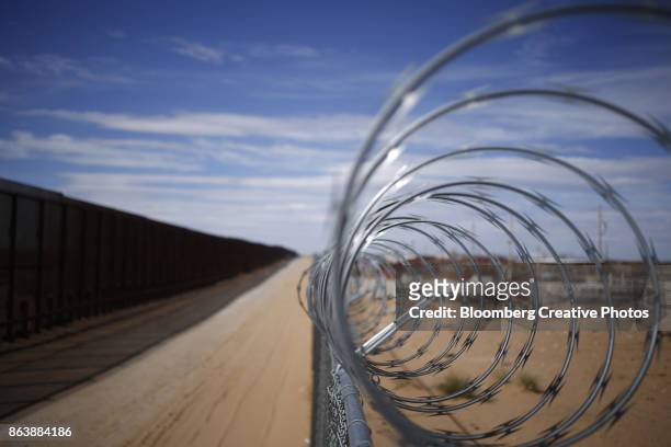 a concertina barbed wire fence stands next to a border fence that separates the u.s. and mexico - national border bildbanksfoton och bilder