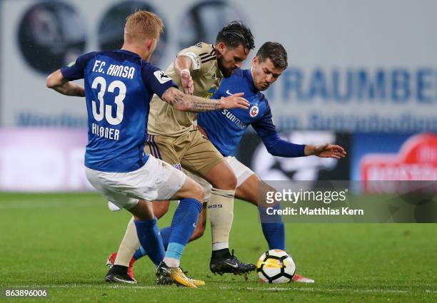 Marcel Hilssner, Marcos Alvarez and Julian Riedel battle for the ball during the third league match between FC Hansa Rostock and VfL Osnabrueck at...