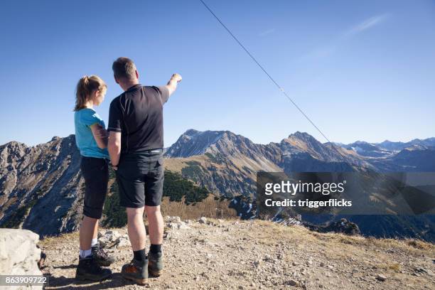 father with daughter on top of the beautiful allgaeu alps - tochter zeigt stock-fotos und bilder