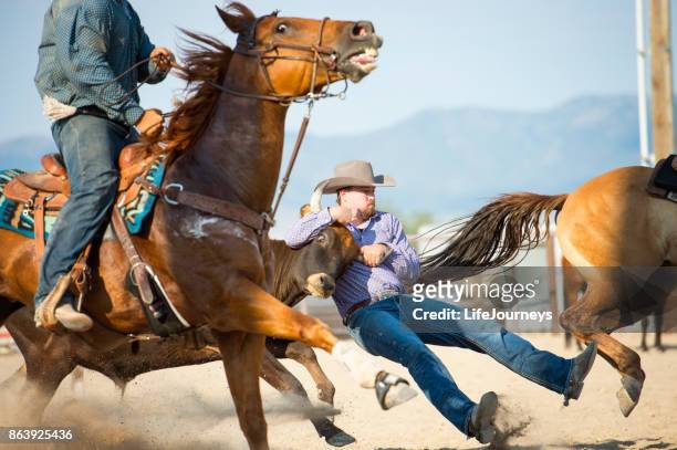 cowboy in mid-action of steer wrestling at a rodeo - defeat fear stock pictures, royalty-free photos & images