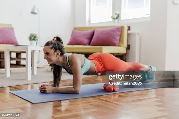 mujer joven haciendo ejercicio de tablón en su casa - tablón fotografías e imágenes de stock