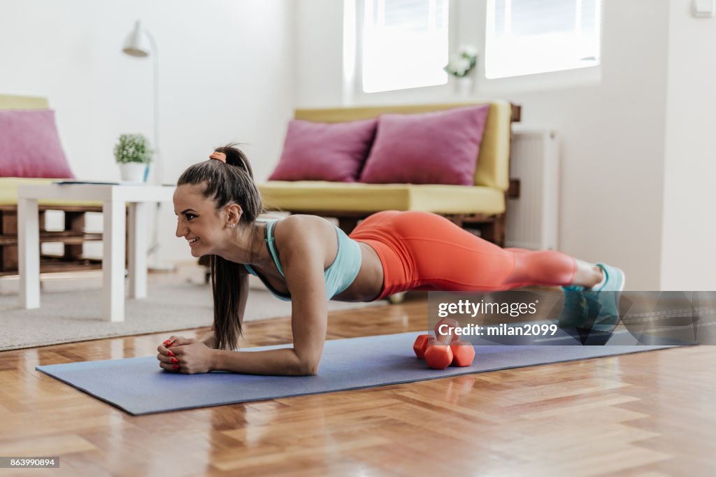 Jeune femme de faire de l’exercice de la planche chez elle