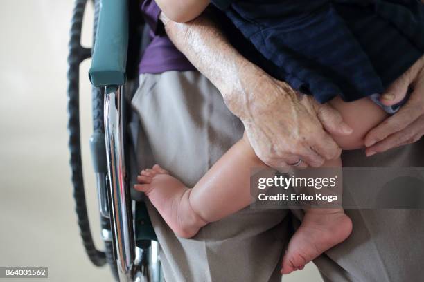 great grandmother holding her great granddaughter on wheelchair - great grandmother imagens e fotografias de stock