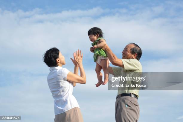 grandfather lifting up granddaughter and grandmother crapping her in the open air - japanese baby photos et images de collection