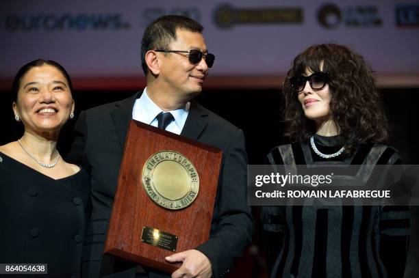 Chinese Director Wong Kar-wai and his wife Esther react after he received the Lumiere Award from French actress Isabelle Adjani during the ninth...