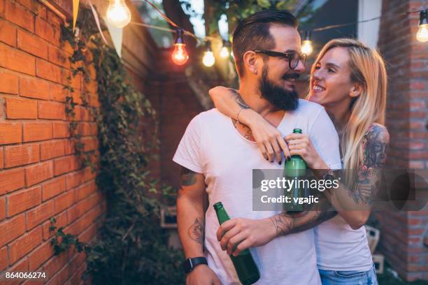 tattooed couple having fun at barbecue in backyard - couple grilling stock pictures, royalty-free photos & images