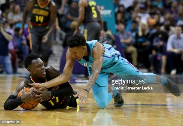 Malik Monk of the Charlotte Hornets goes after a loose ball against Dennis Schroder of the Atlanta Hawks during their game at Spectrum Center on...