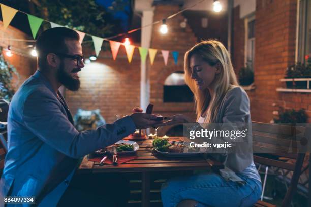 tattooed couple having romantic backyard barbecue dinner with proposal - date night stock pictures, royalty-free photos & images