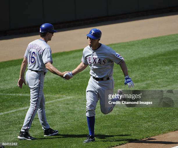 Outfielder David Murphy of the Texas Rangers shakes hands with thirdbase coach Dave Anderson after collecting his first hit of the season, a solo...