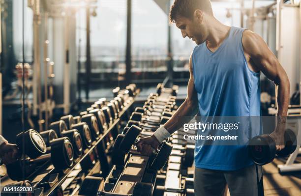 deportista musculoso teniendo pesos de un rack en un gimnasio. - mancuerna fotografías e imágenes de stock