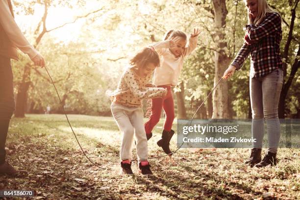 vrolijke familie spelen met springtouw samen in het park. - jump rope stockfoto's en -beelden