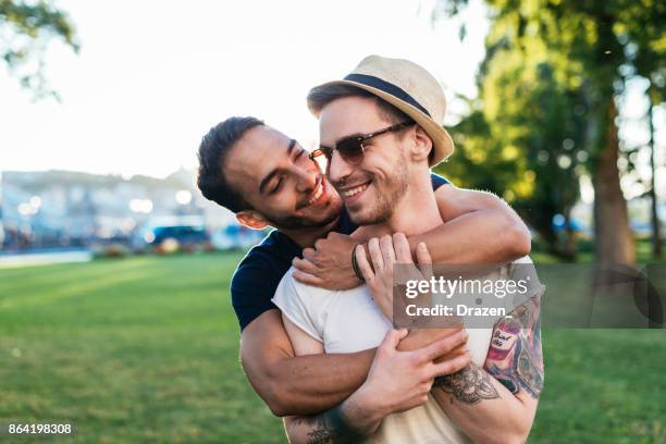 cheerful gay couple expressing love to each other while on vacation - gay kiss stock pictures, royalty-free photos & images