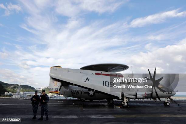 Crew members guard in front of E-2 Hawkeye on the deck of the U.S. Aircraft carrier Ronald Reagan on October 21, 2017 in Busan, South Korea. The...