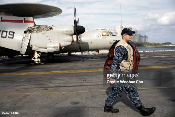 Crew member passes by E-2 Hawkeye on the deck of the U.S. Aircraft carrier Ronald Reagan on October 21, 2017 in Busan, South Korea. The...
