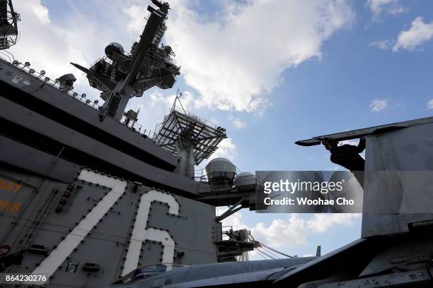Crew member tends to an F/A-18 E/F Super Hornet on the deck of the U.S. Aircraft carrier Ronald Reagan on October 21, 2017 in Busan, South Korea. The...