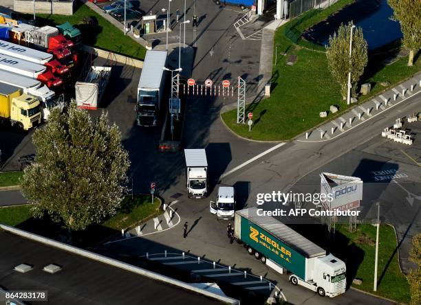 This aerial view shows French police officers control a truck on October 14, 2017 by a petrol station, near the former "Jungle" migrant camp that was...