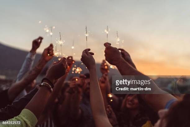 amigos celebrando año nuevo en la azotea - celebration fotografías e imágenes de stock