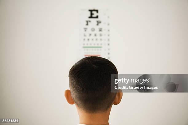 young boy looking at wall eye chart - sight test chart stock pictures, royalty-free photos & images