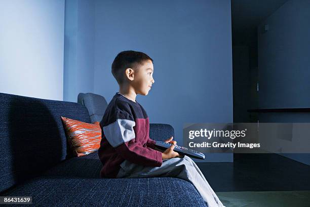 young boy sitting alone watching tv - boy watching tv stock pictures, royalty-free photos & images