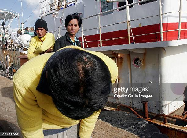 Crew members look at their boat after ten Vietnamese nationals were arrested following a mutiny on a fishing vessel, the Balena, outside Cape Town's...